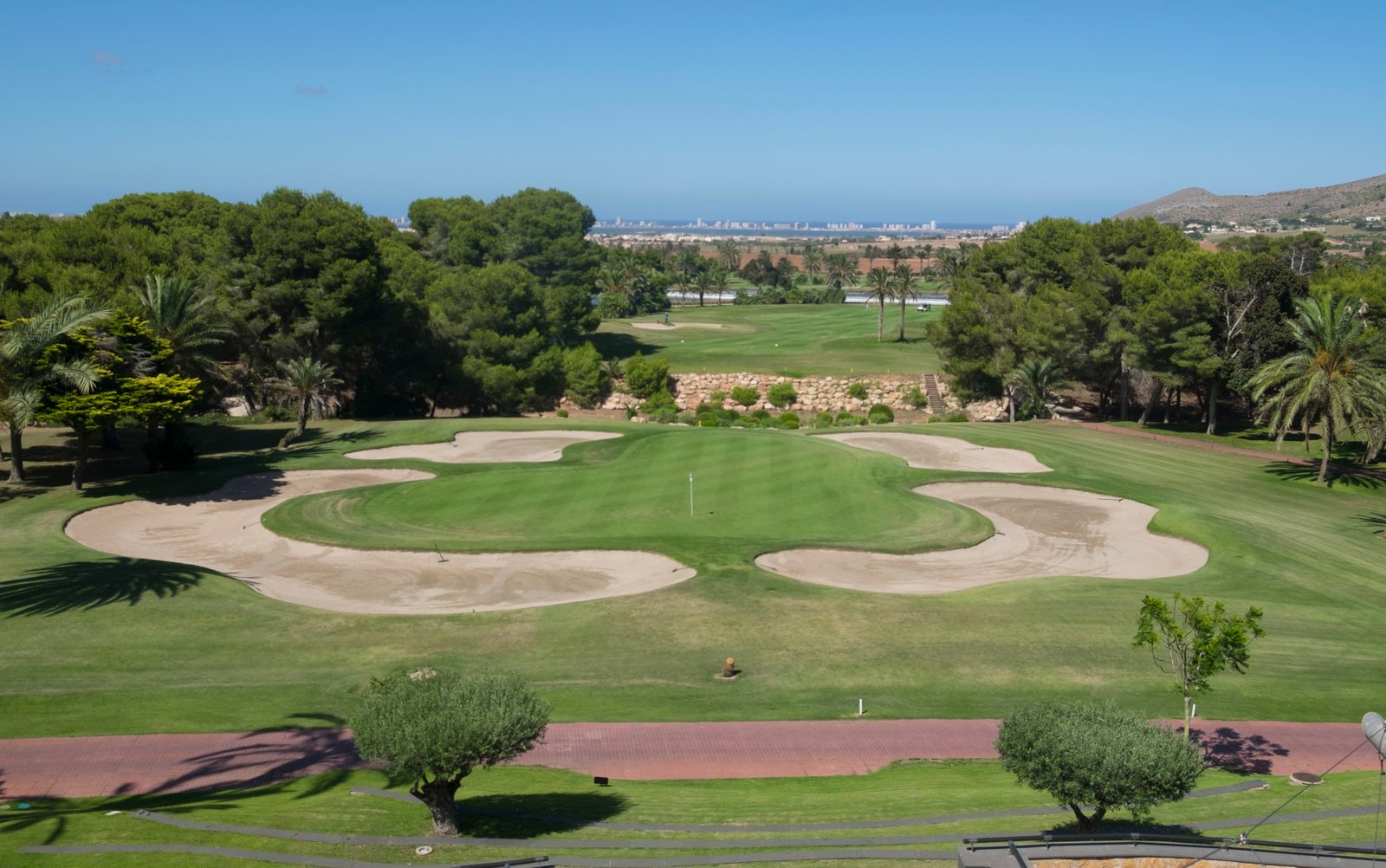 Golfgreen omringd door zandbunkers en bomen, nabij nieuwbouw in La Manga Club