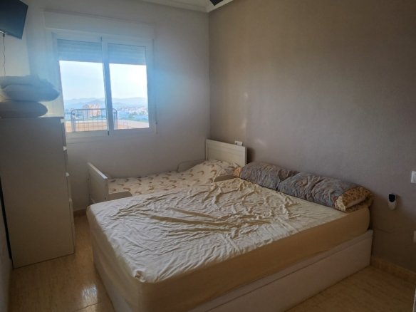 Slaapkamer met tweepersoonsbed en raam in het appartement in La Manga.