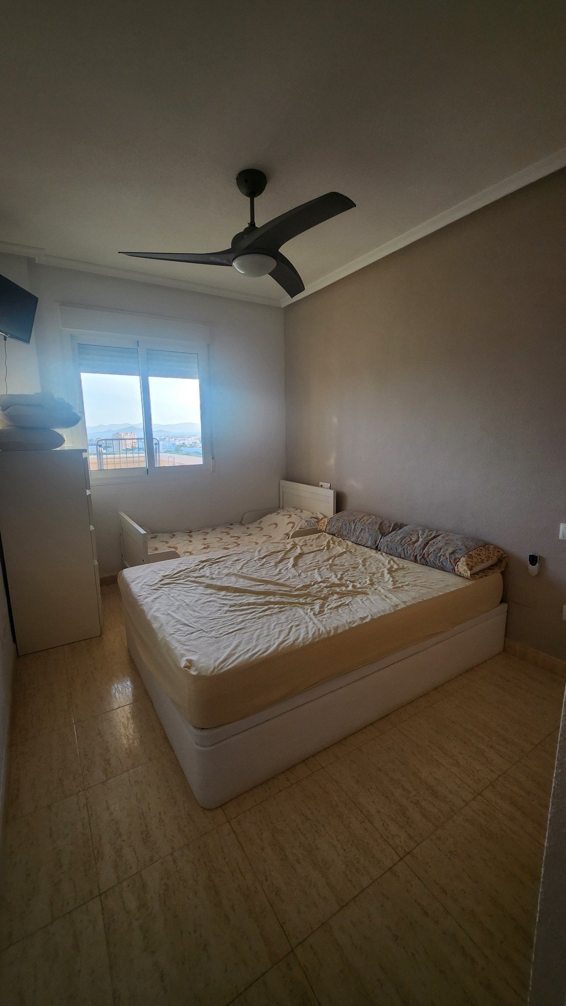 Slaapkamer met tweepersoonsbed en raam in het appartement in La Manga.