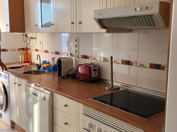 Keuken met bovenkasten, kookplaat en oven in het appartement in La Manga.