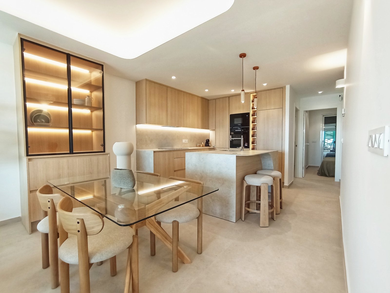 Moderne keuken met houten kasten en een eetruimte met een glazen tafel.