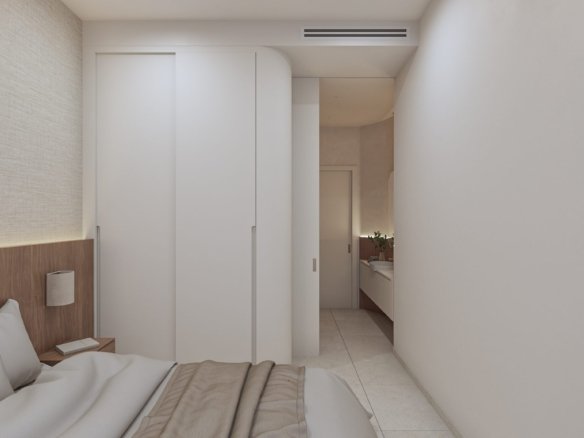 Slaapkamer met een bed, ingebouwde kasten en een doorgang naar een wastafelruimte.