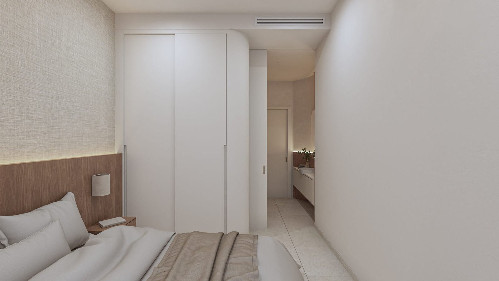 Slaapkamer met een bed, ingebouwde kasten en een doorgang naar een wastafelruimte.