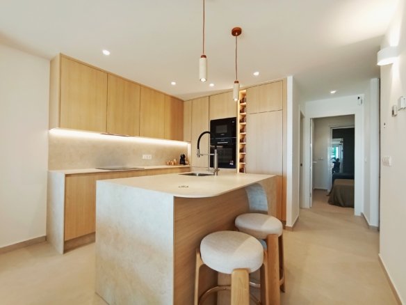 Moderne keuken met houten kasten en een eiland met barstoelen.