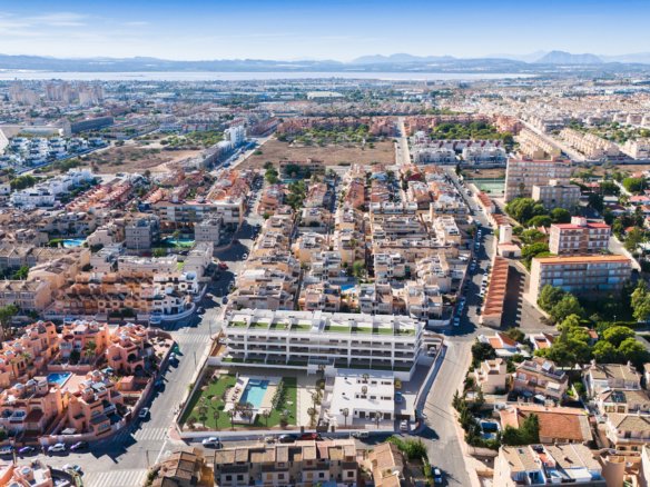 Luchtfoto van een woninggebied met verschillende huizen en een nieuwbouwcomplex met zwembad.