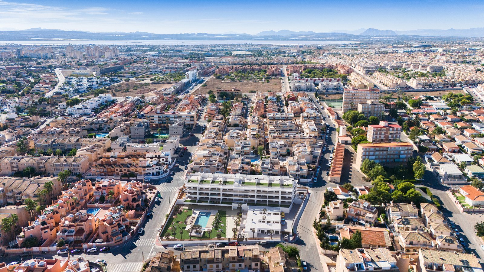 Luchtfoto van een woninggebied met verschillende huizen en een nieuwbouwcomplex met zwembad.