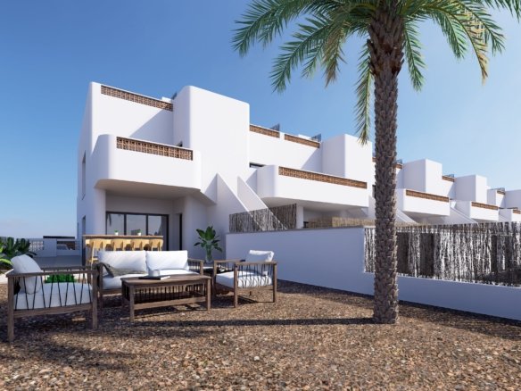 Modern wit gebouw met een terras en loungemeubels, omringd door planten en palmbomen.