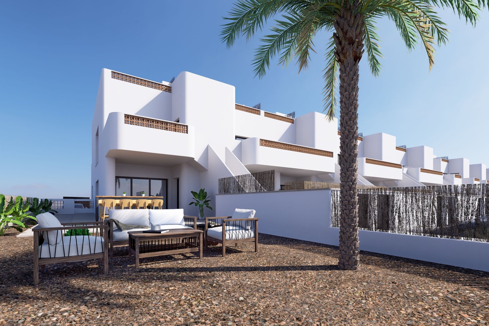 Modern wit gebouw met een terras en loungemeubels, omringd door planten en palmbomen.