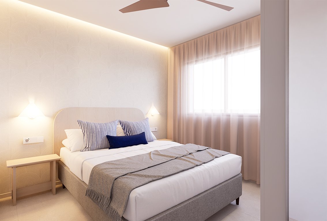 Een slaapkamer met een bed, kussens en een raam achter een gordijn.