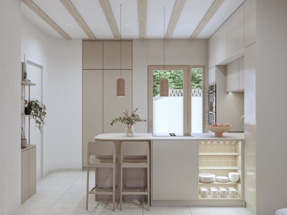 Lichte keuken met kookeiland, twee barkrukken, kasten en een raam.