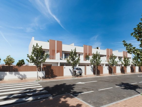 Straatbeeld met een rij moderne woningen, voortuinen achter lage muren en een auto bij een toegang van Geschakelde woning kopen in San Pedro.