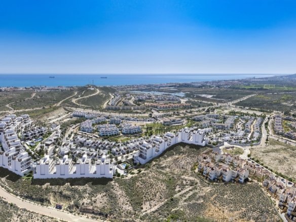 Luchtbeeld van een woonwijk met witte gebouwen en woningen in een droog landschap aan zee.