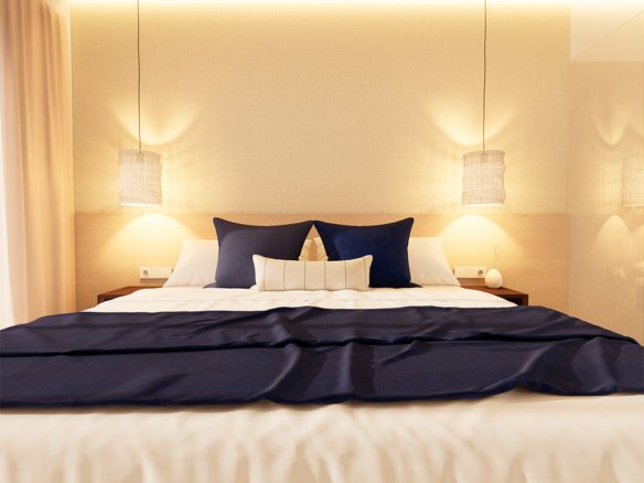 Slaapkamer met bed, blauwe kussens en hanglampen.