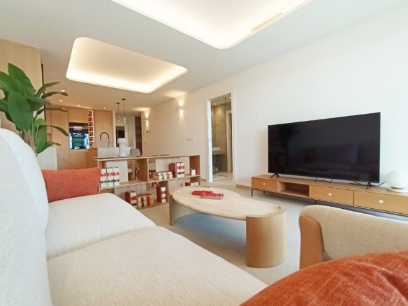 Moderne woonkamer met open keuken, een bank, een tafel en een televisie.