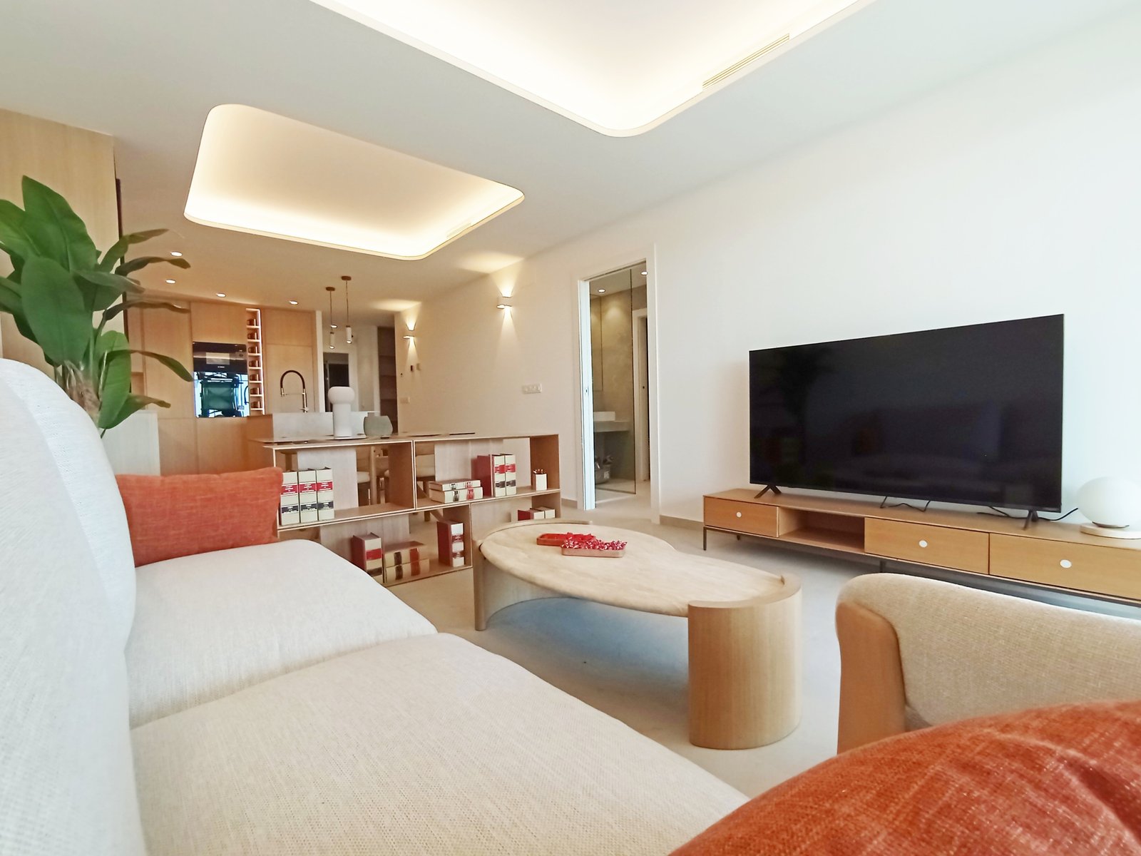 Moderne woonkamer met open keuken, een bank, een tafel en een televisie.