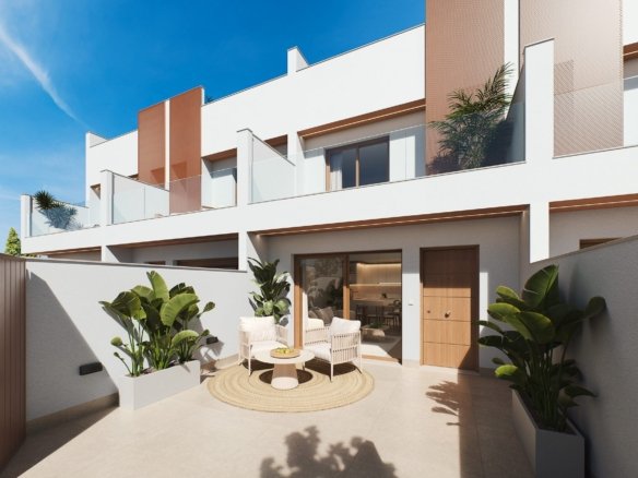 Zonnig terras met zitje en planten voor een moderne woning; op de achtergrond zijn woningen met glazen balkons te zien.