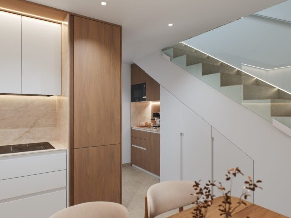 Moderne keuken met kookplaat en kasten naast een trap met glazen balustrade.