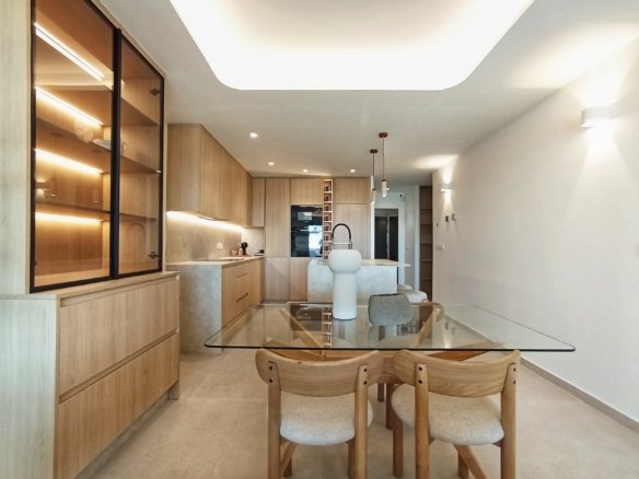 Moderne keuken en eetruimte met houten kasten en glazen tafel.