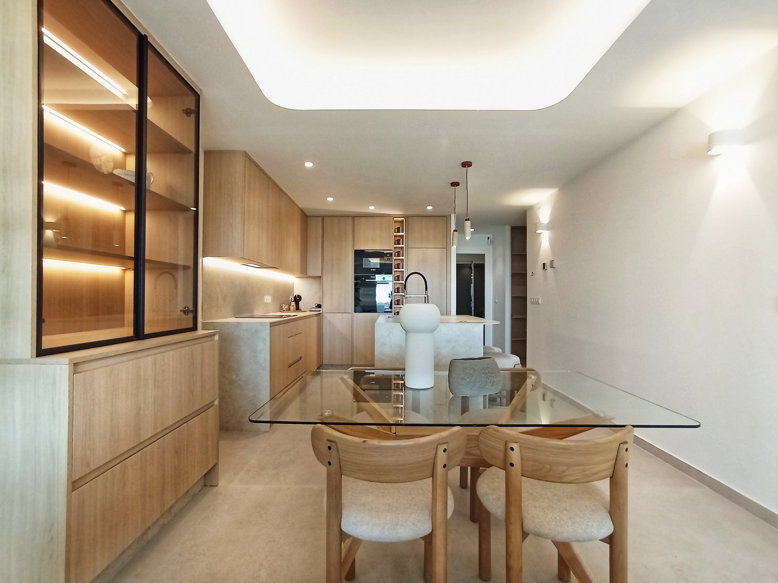 Moderne keuken en eetruimte met houten kasten en glazen tafel.
