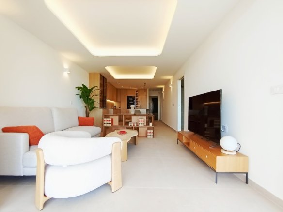 Moderne woonkamer met open keuken, bank en televisiemeubel.