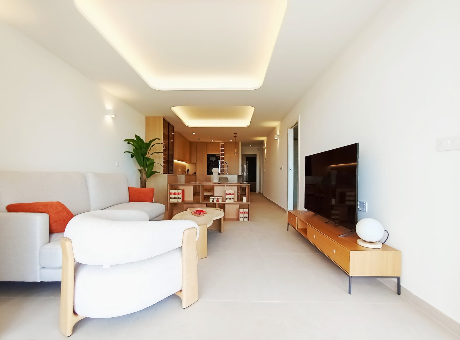 Moderne woonkamer met open keuken, bank en televisiemeubel.